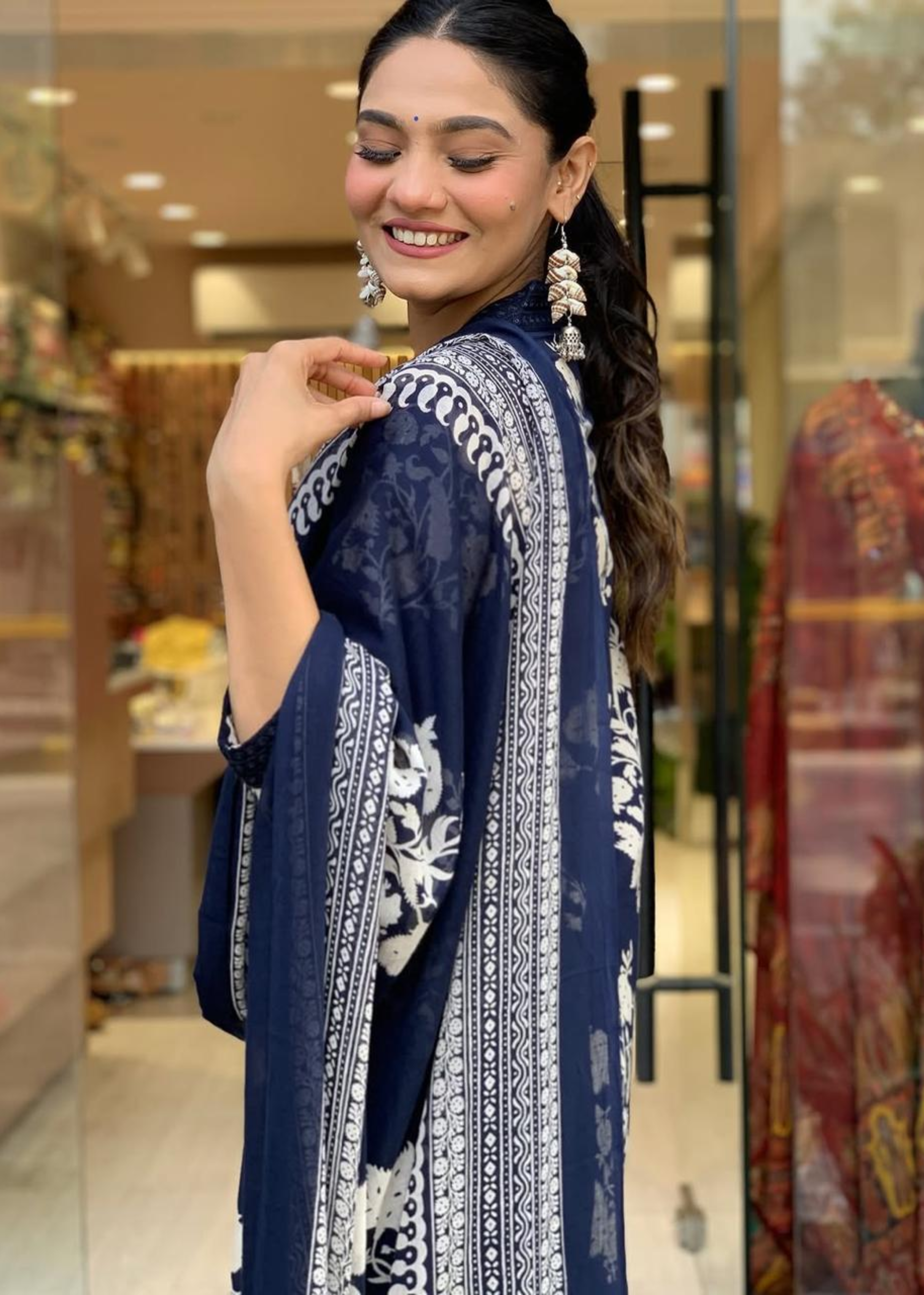 Elegant navy and white A-line kurta with floral prints, pleated V-neck design, paired with matching palazzos and dupatta.